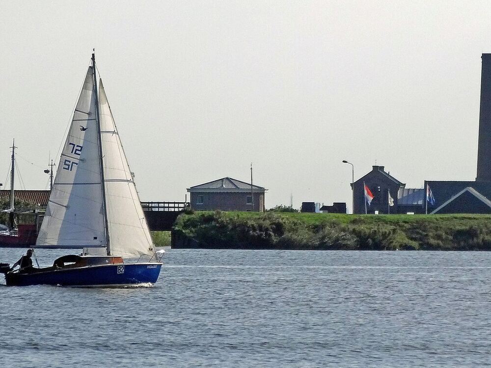 Zeilboot vaart over het Nijkerkernauw bij Nijkerk, met stoomgemaal Hertog Reijnout aan de oever